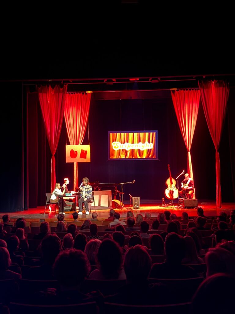Theaterpodium met warme rode belichting tijdens een voorstelling